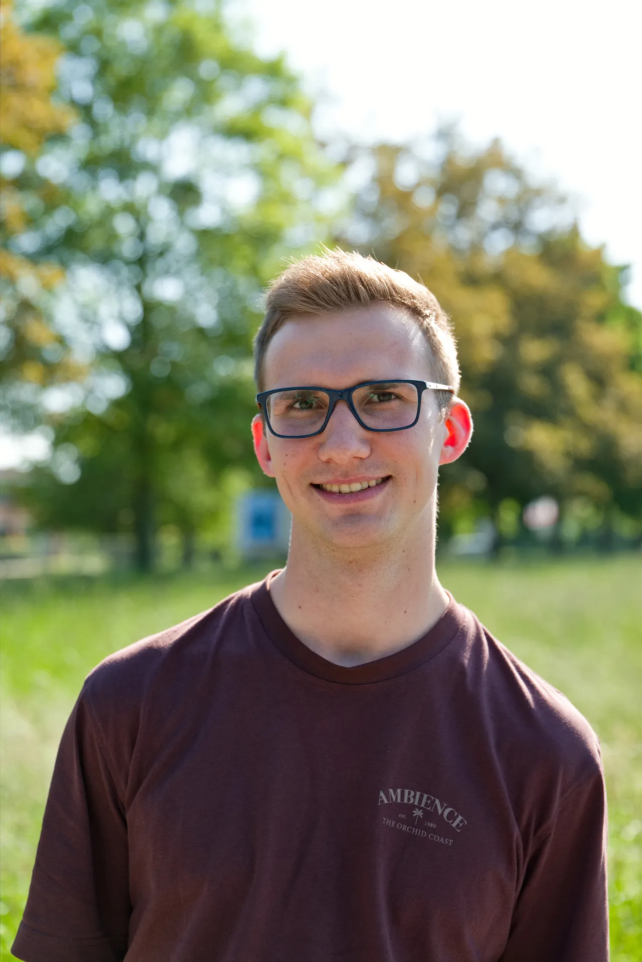 Porträt eines jungen Mannes mit Brille im Grünen