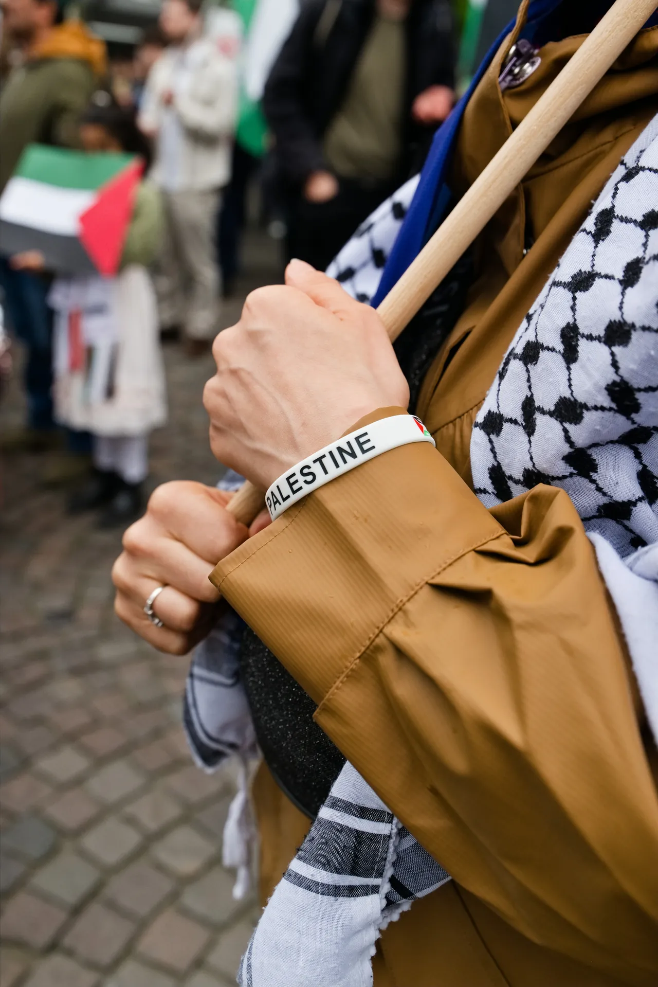 Hand an einer Fahnenstange neben einem palästinensischen Tuch